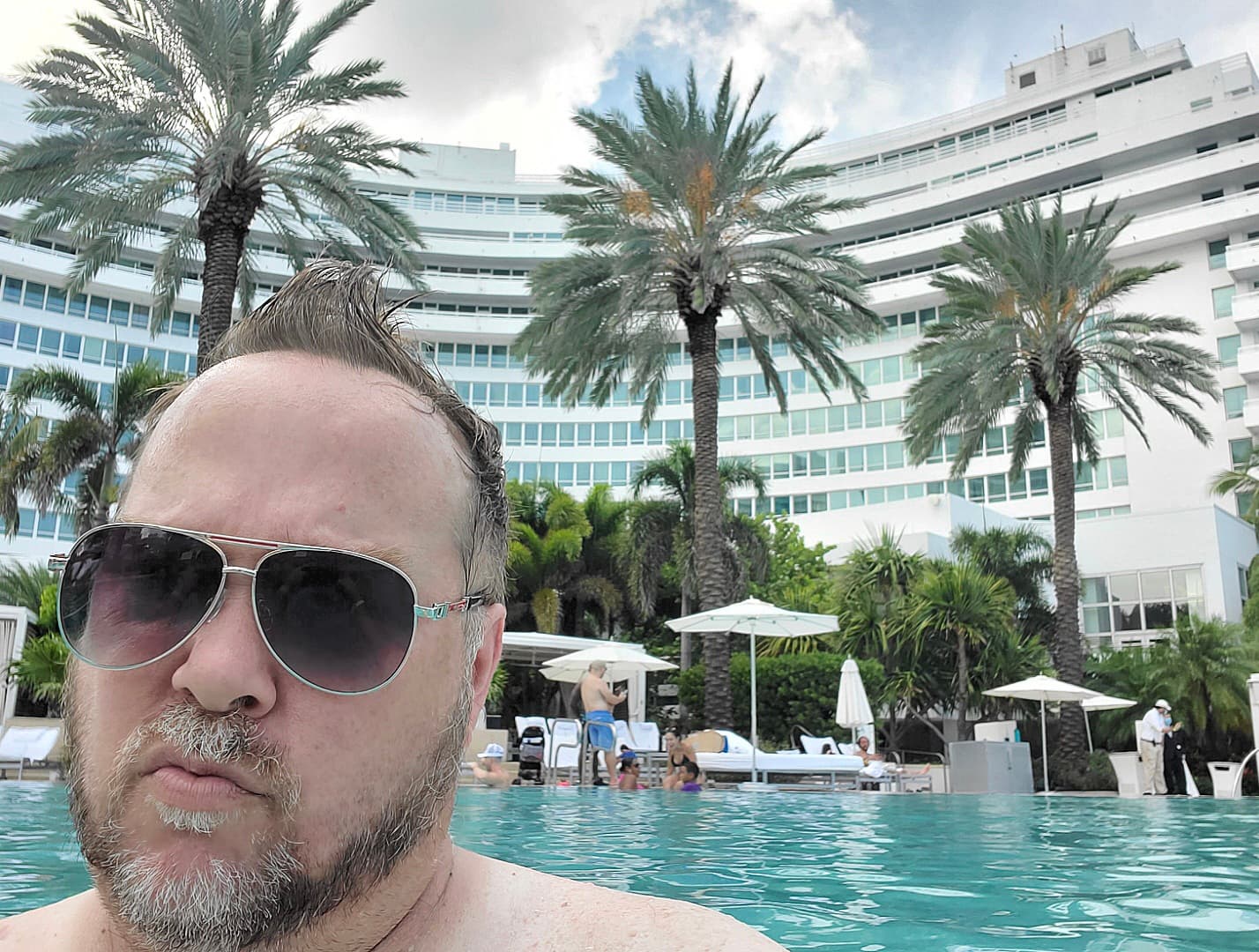 Kene Bell beside a resort pool lined with palm trees