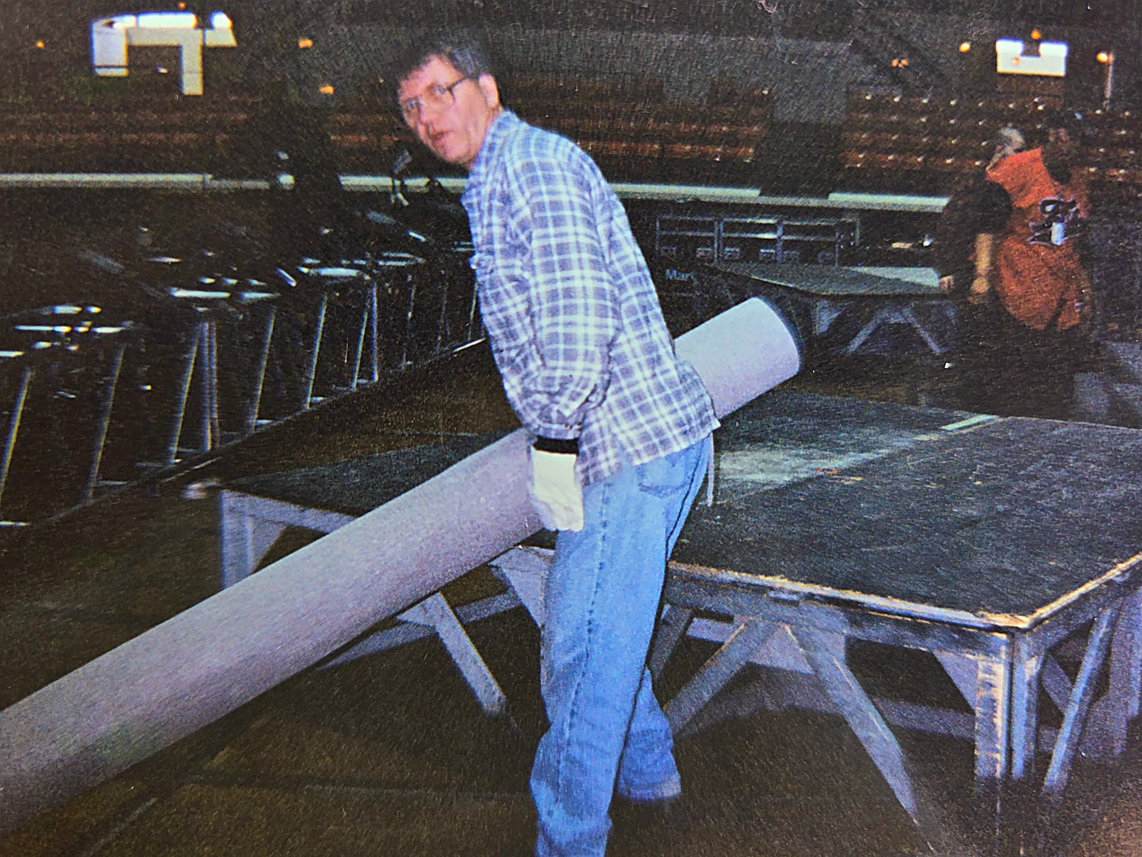 A Shout 2000 stage hand carrying a rolled rug during load-in