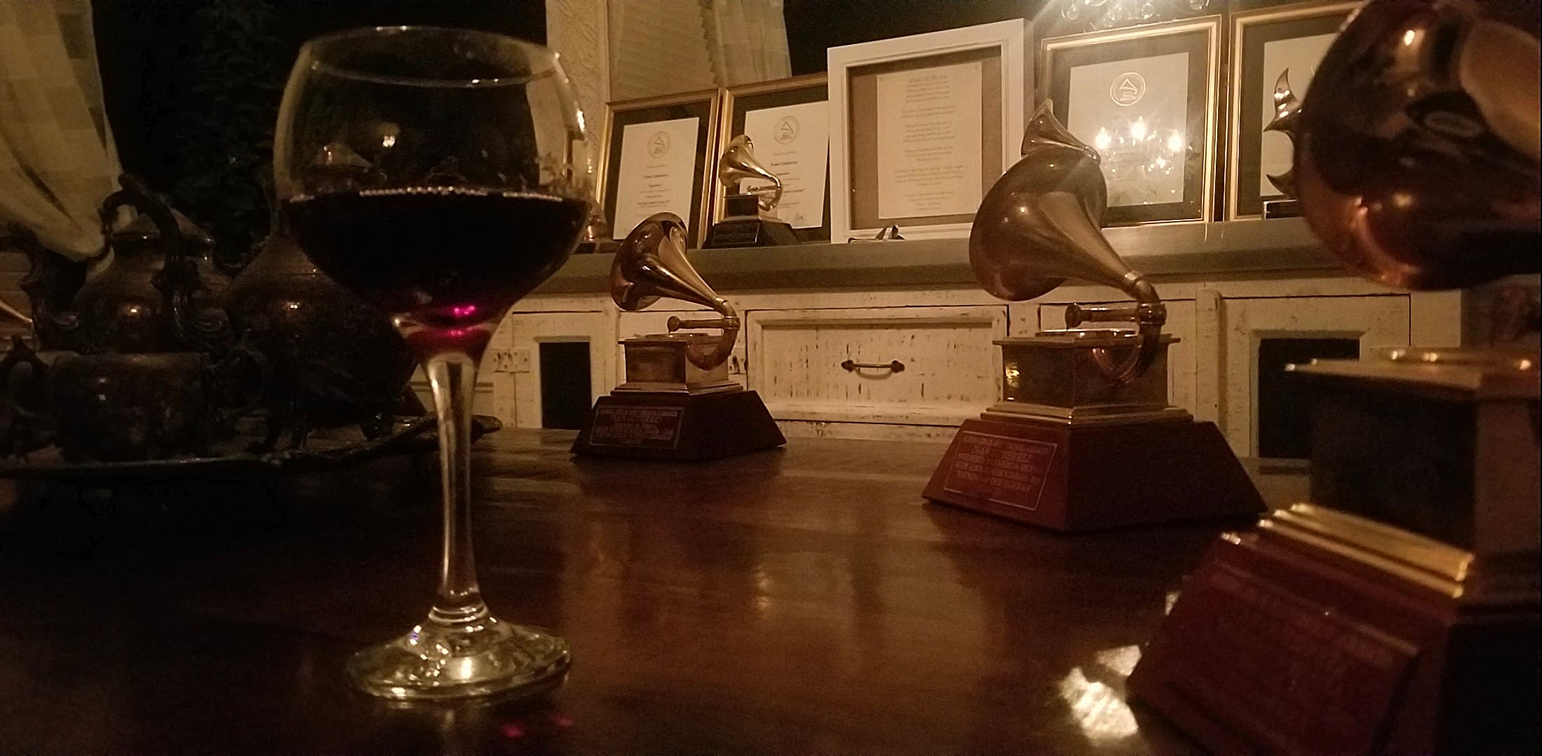 Awards, framed certificates, and a wine glass photographed at table level