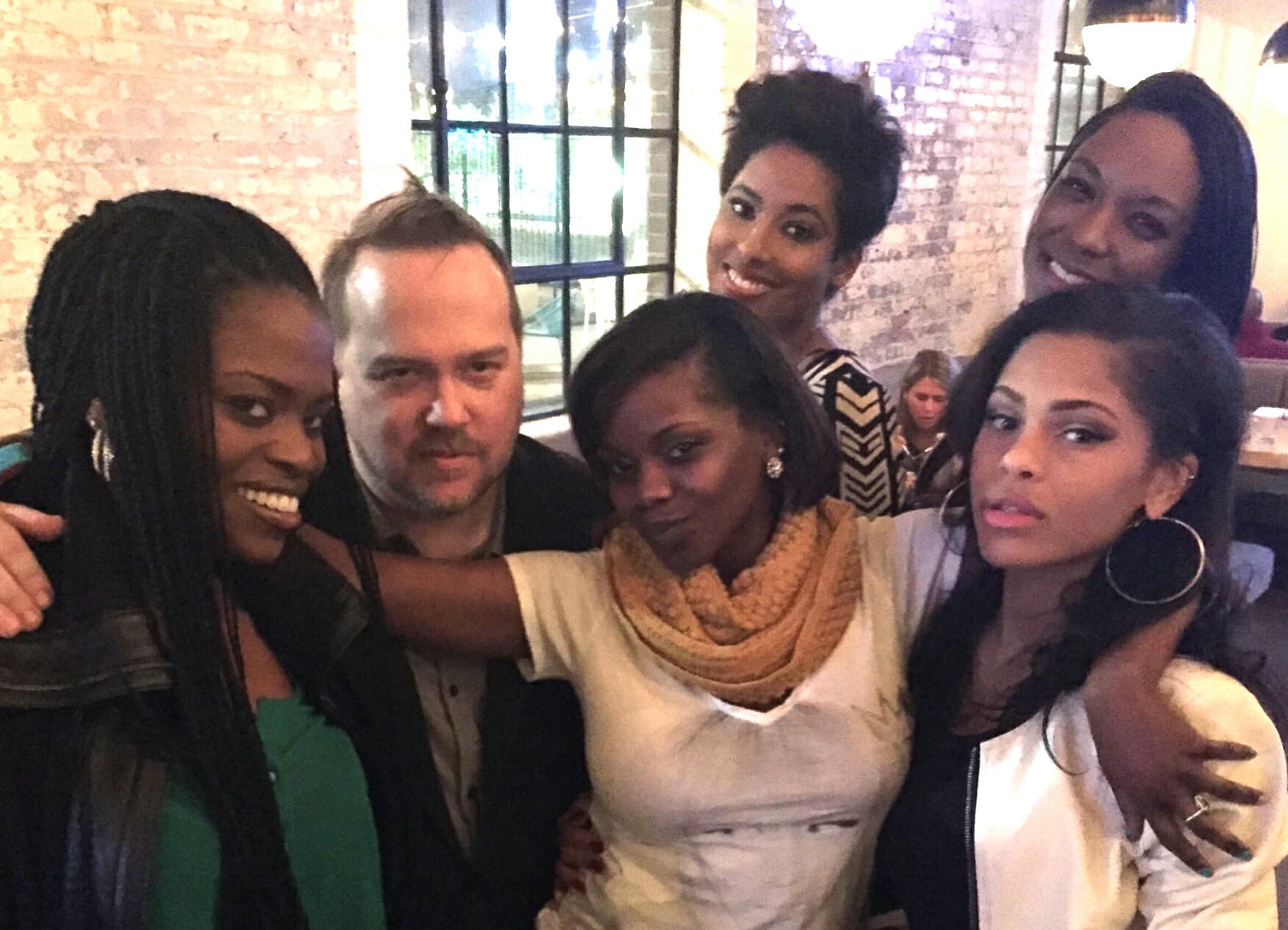 Kene Bell surrounded by friends at an indoor gathering