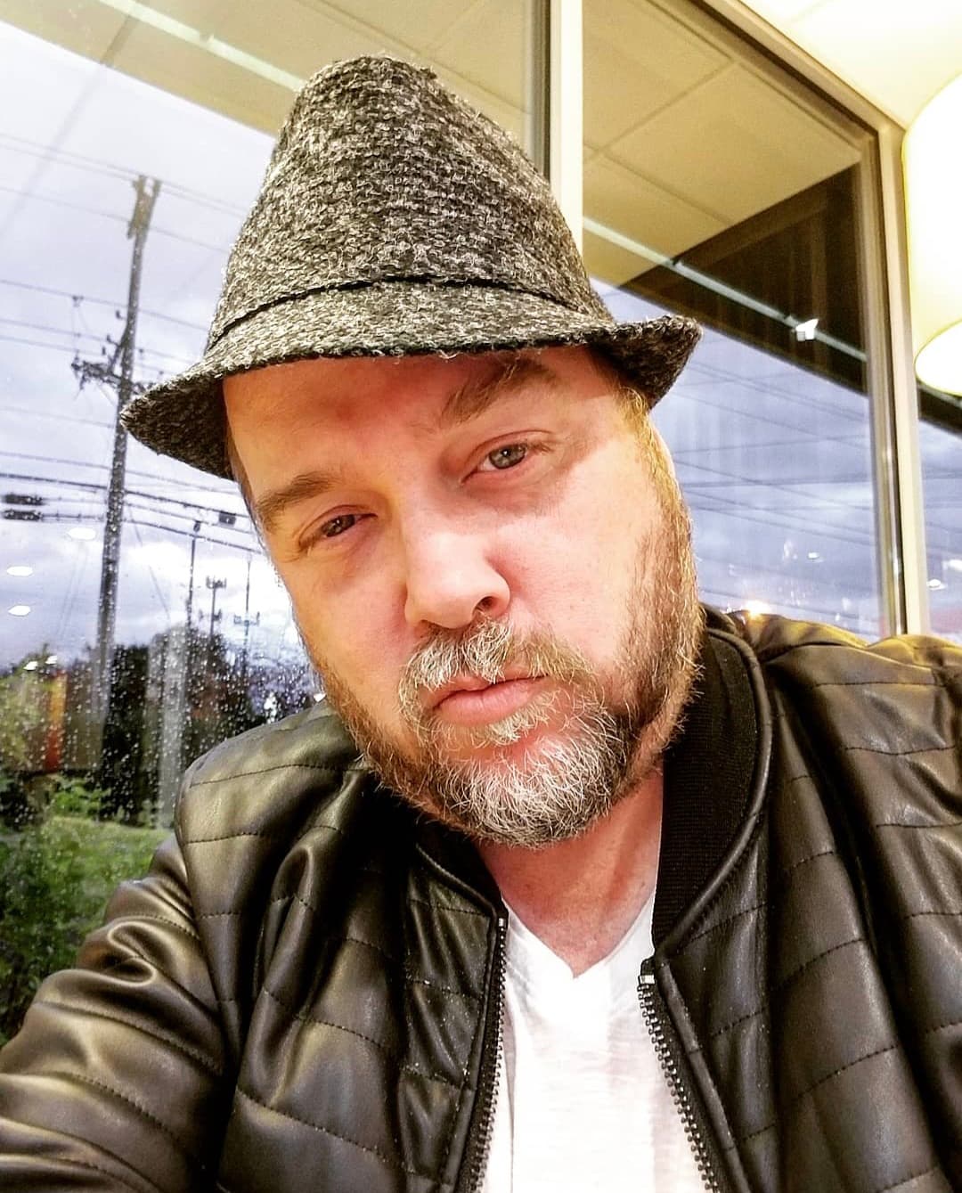 Kene Bell wearing a fedora and black leather jacket