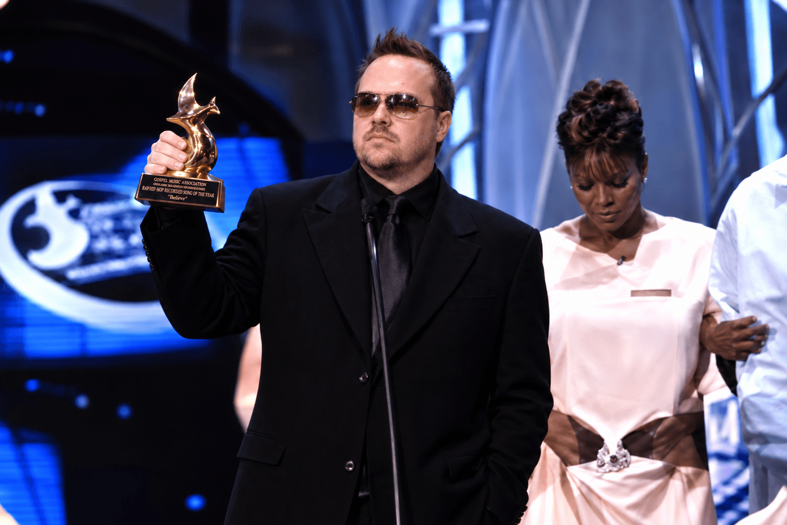 Kene Bell holding up a Dove Award during the on-stage acceptance