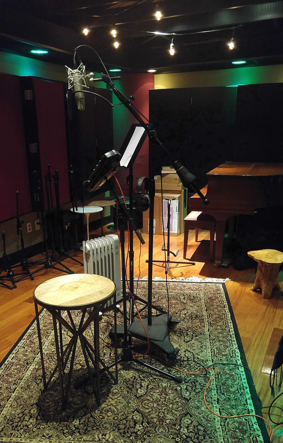Professional live room set for recording with microphones, a piano, stools, and acoustic treatment