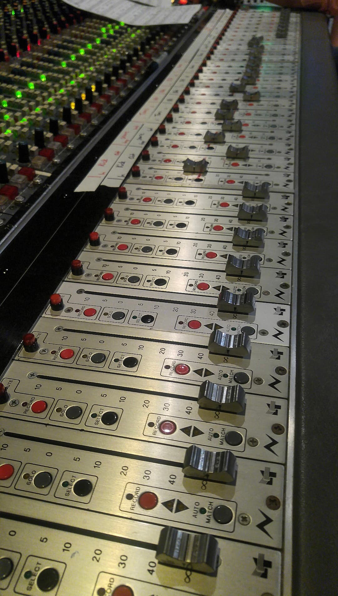 Close vertical view along professional console faders and channel strips
