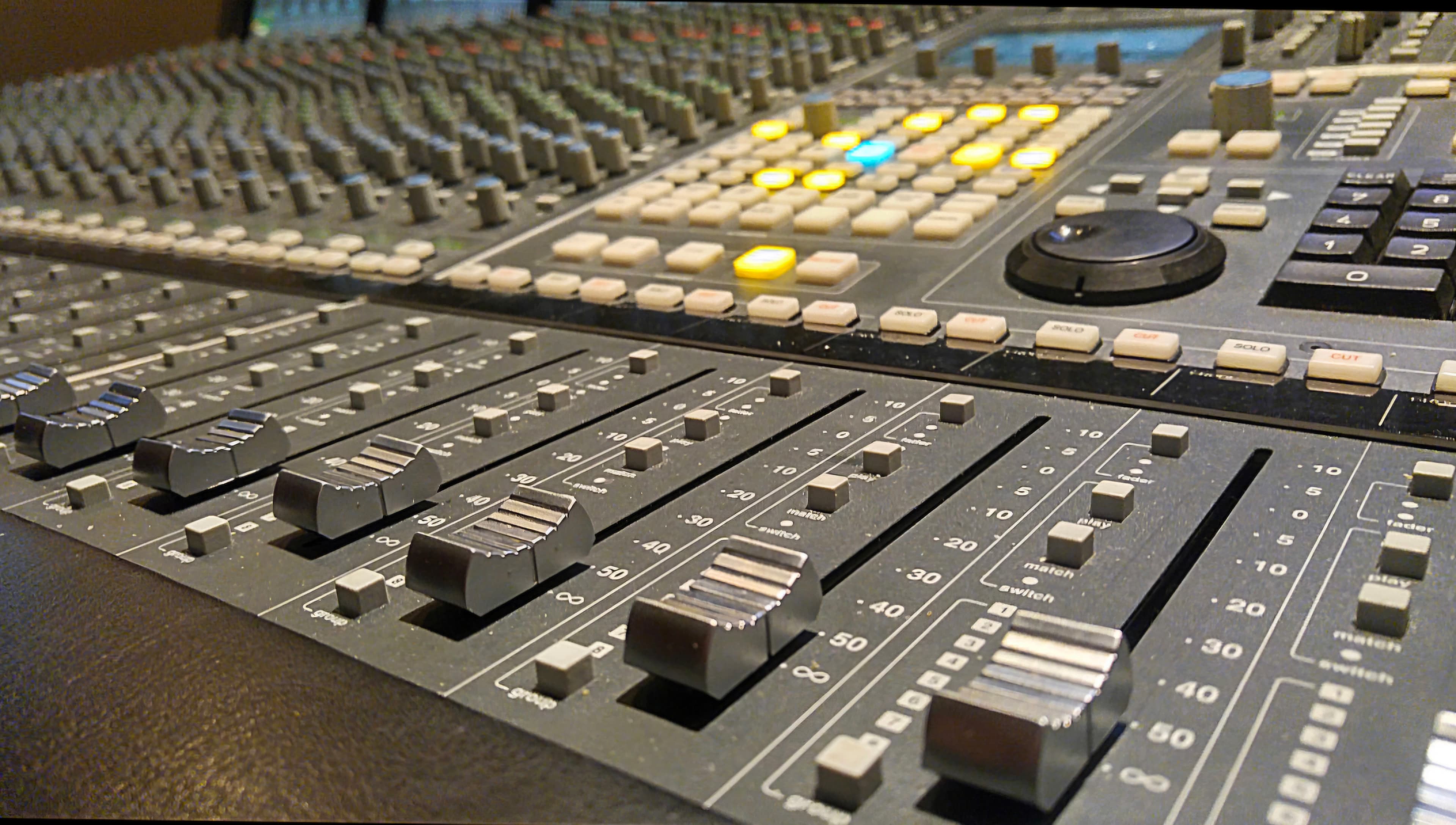 Close landscape view across professional console faders and control surfaces