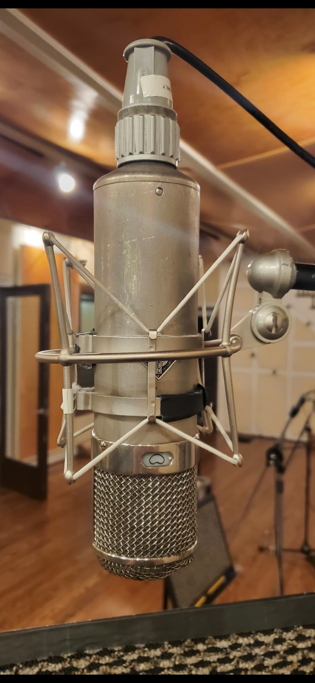 Close view of a vintage-style Neumann studio microphone in its shock mount
