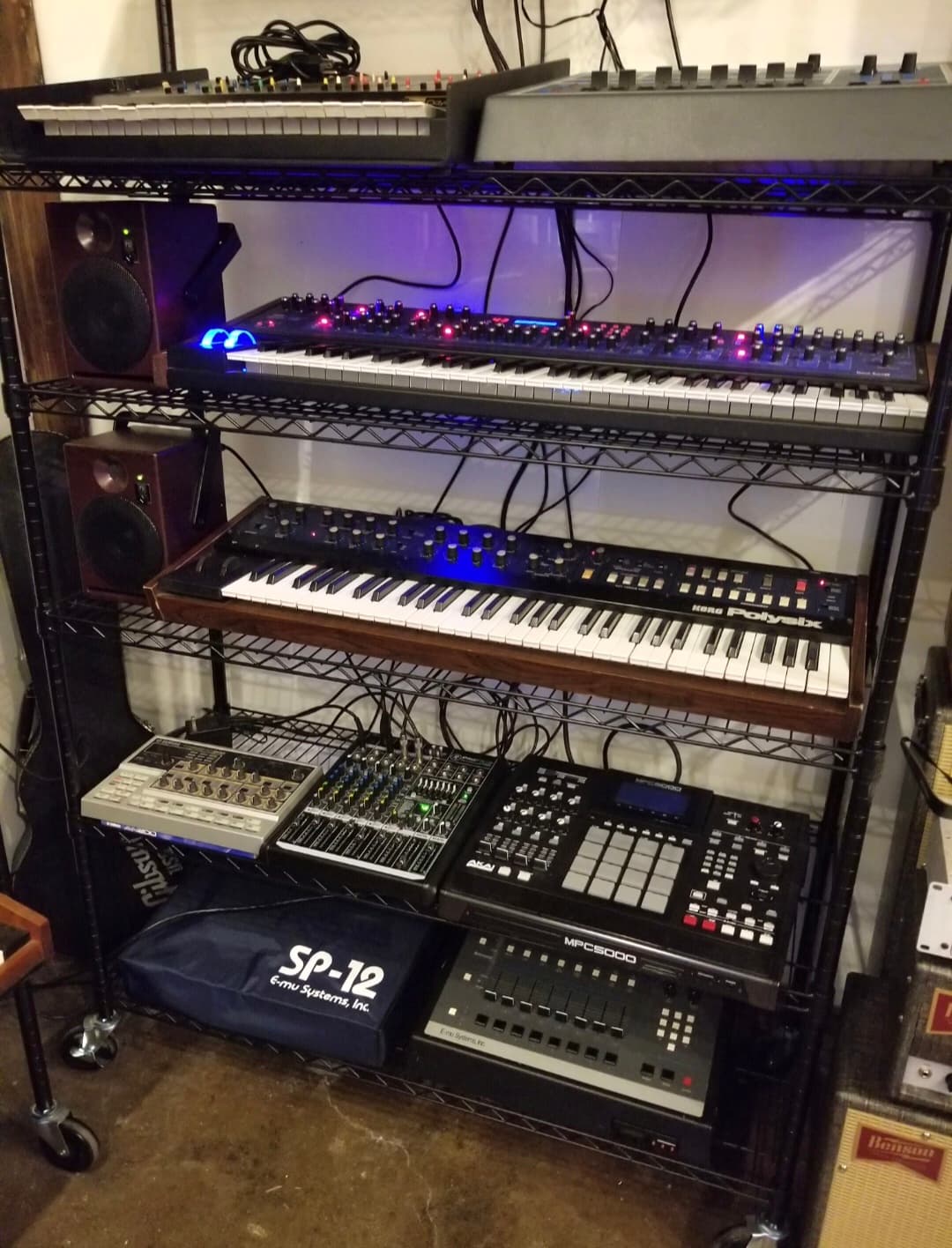 Equipment rack filled with synthesizers, keyboards, and production tools