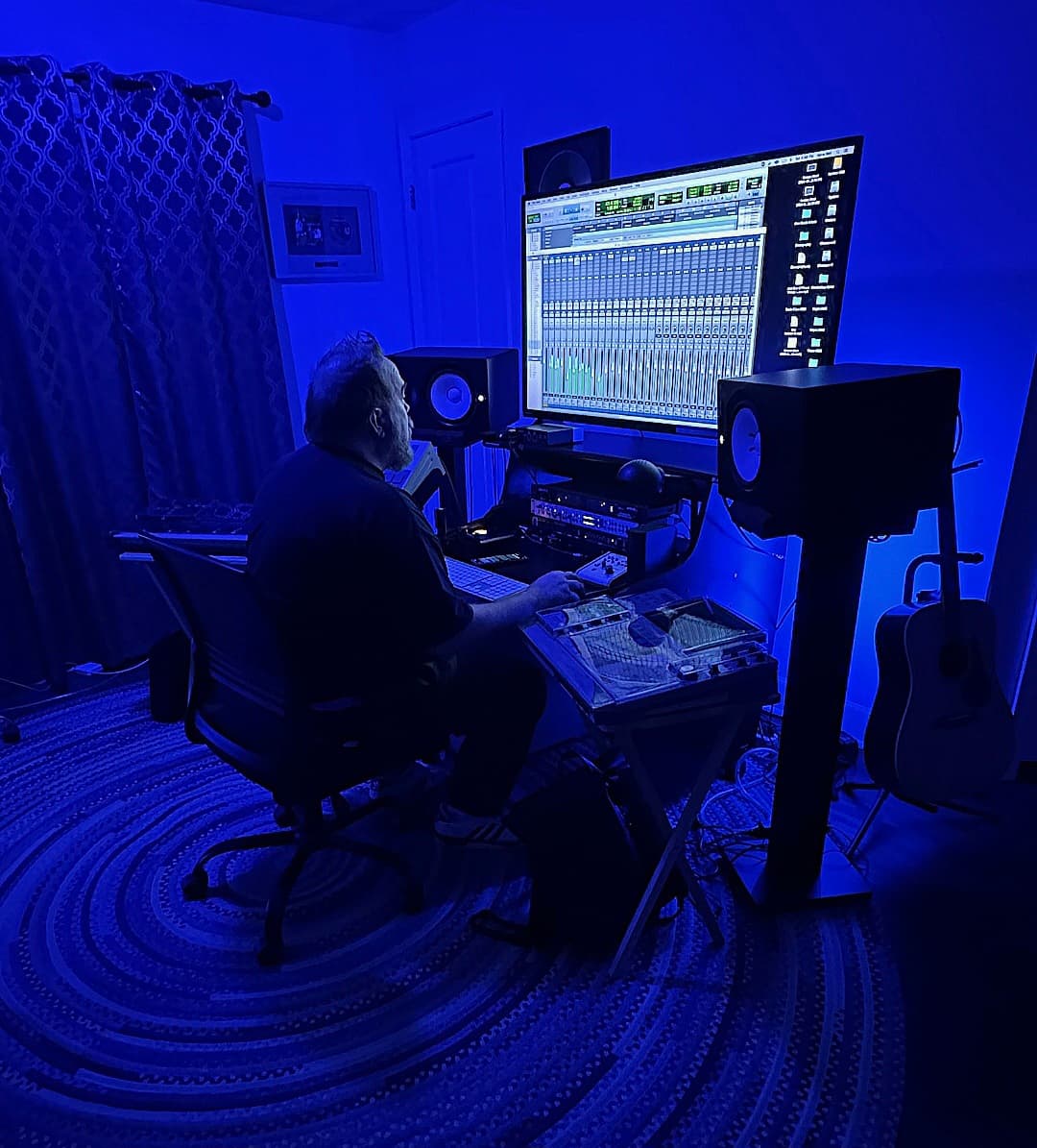 Producer or engineer actively working at a blue-lit Ghostown production workstation