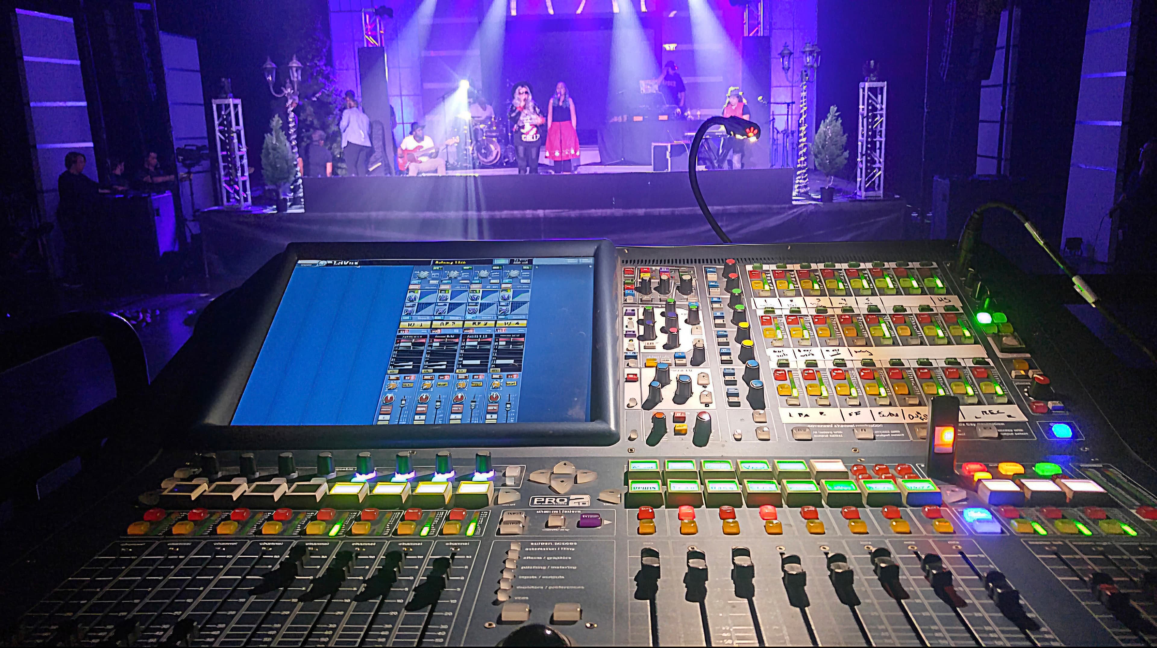 Compact live-sound console positioned toward a smaller illuminated performance stage