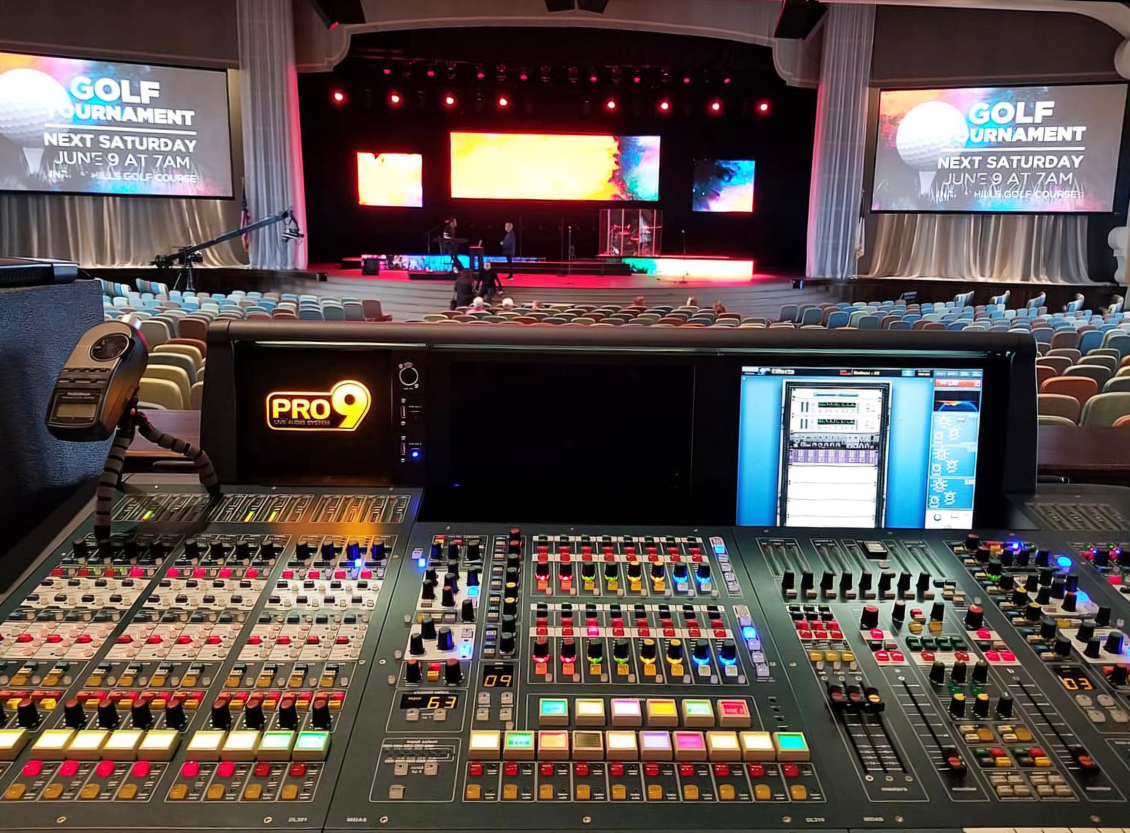 Large PRO9 live-sound console facing an auditorium and illuminated stage