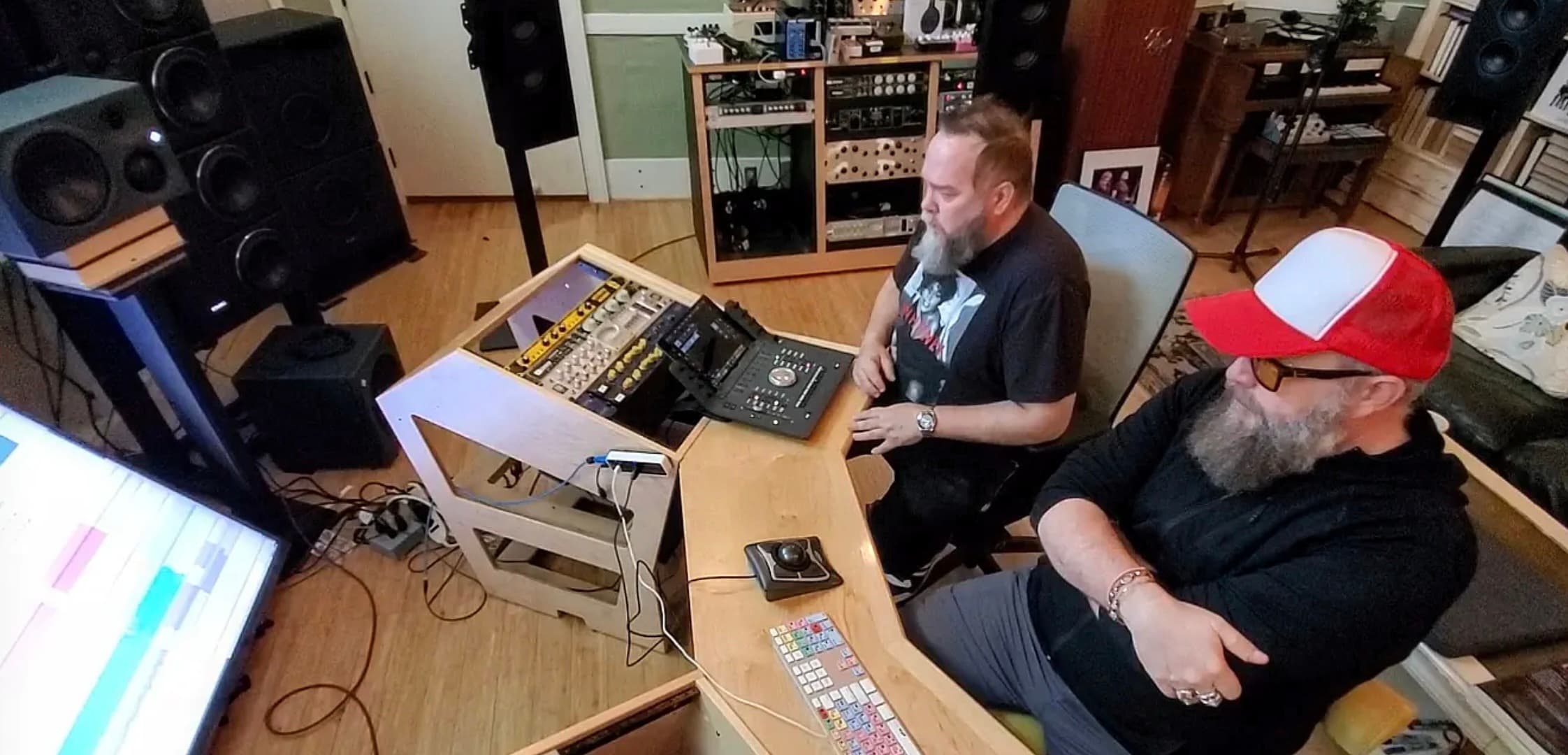 Two unidentified people working and listening together at a professional control-room workstation