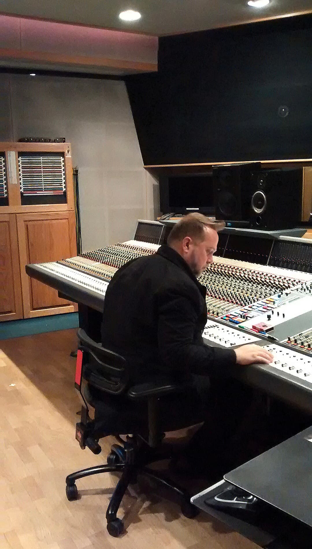 Unidentified engineer seated at a large-format recording console in a professional control room