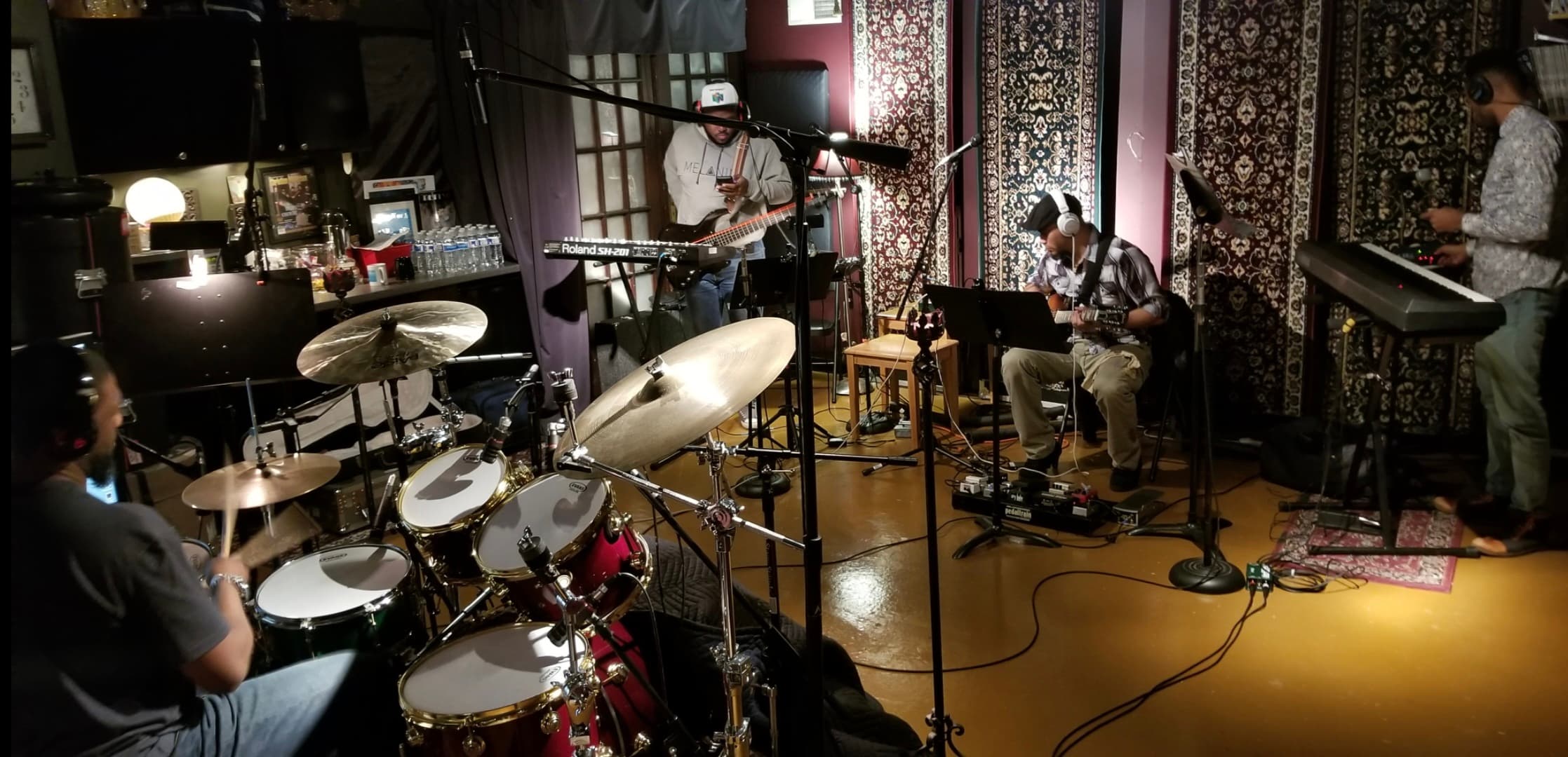 Unidentified musicians tracking together with drums, bass, guitar, keyboards, microphones, and headphones